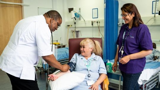 A student nurse testing the blood pressure of another student in a simulation ward